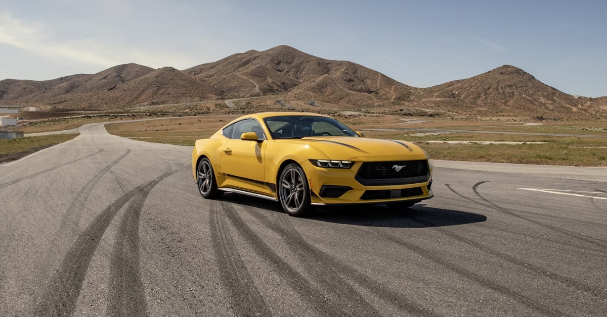 2025 Ford mustang driving on a race track in the desert near the mountains