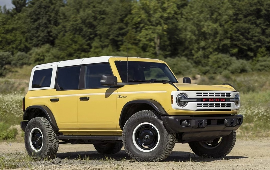 Yellow Ford Bronco parked in front of trees off road