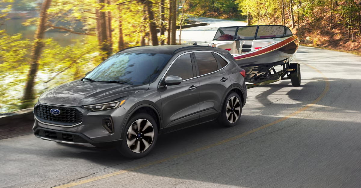 2025 Ford Escape towing a boat through a road in the forest