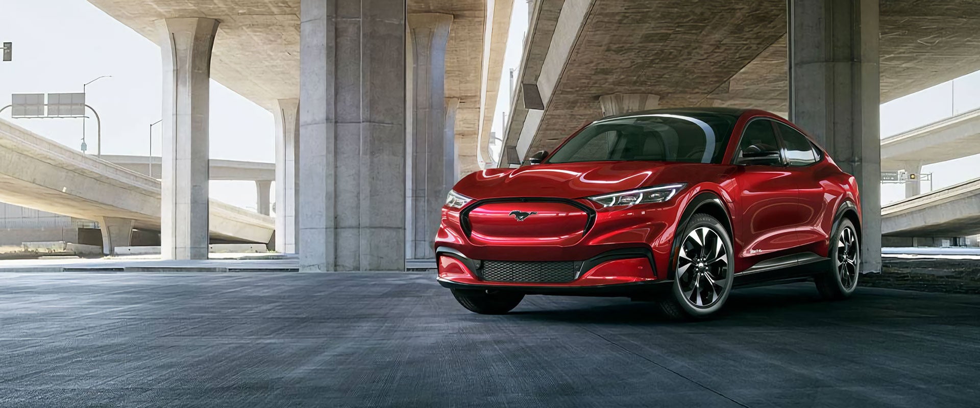 Red Ford Mach-ev parked under flyover