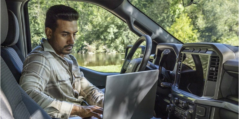 man looking at the laptop in car