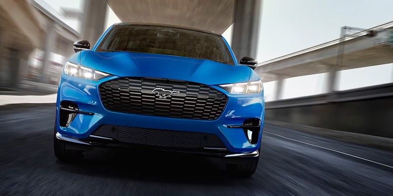 Blue car driving on a road, shown from the front with motion blur in the background