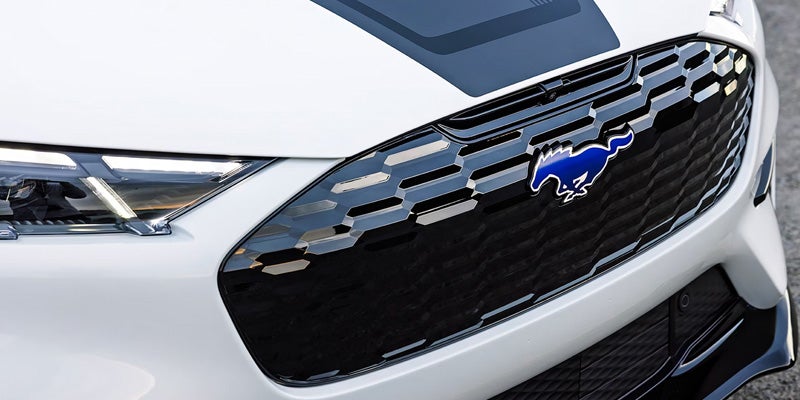 Close-up of a white car’s front grille featuring a black honeycomb pattern