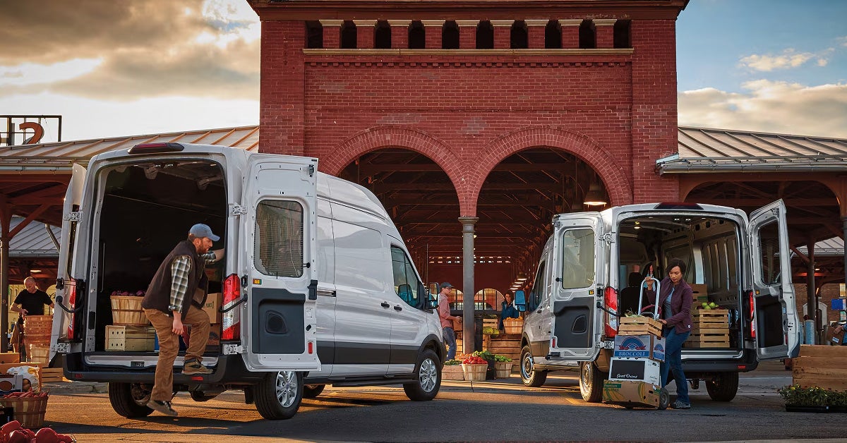 Ford transit vans parked in front of a building with back trunk open